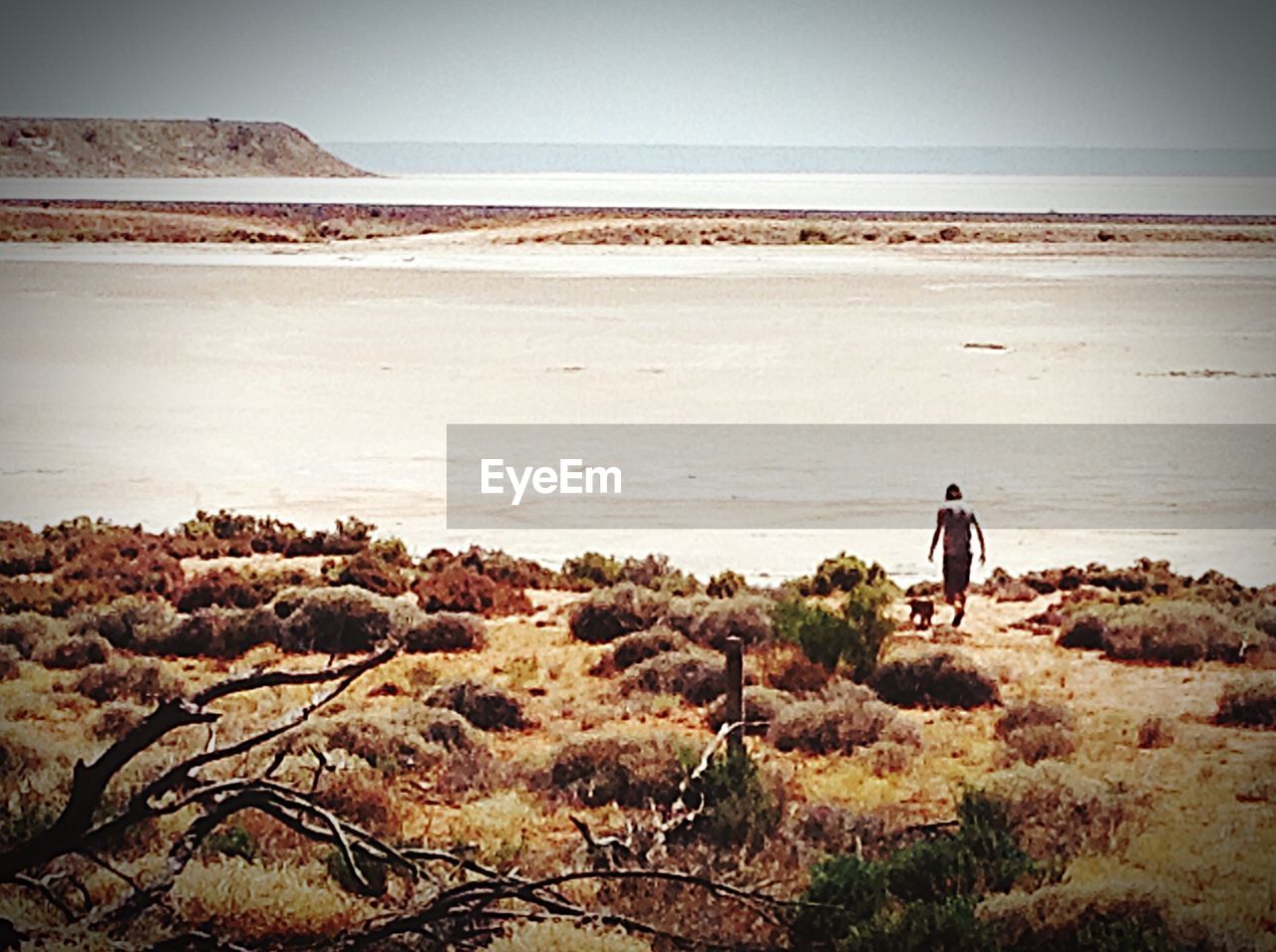 WOMAN SITTING ON ROCK AT SEASIDE