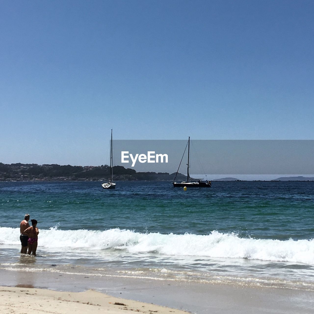 MAN STANDING ON SHORE AGAINST CLEAR SKY