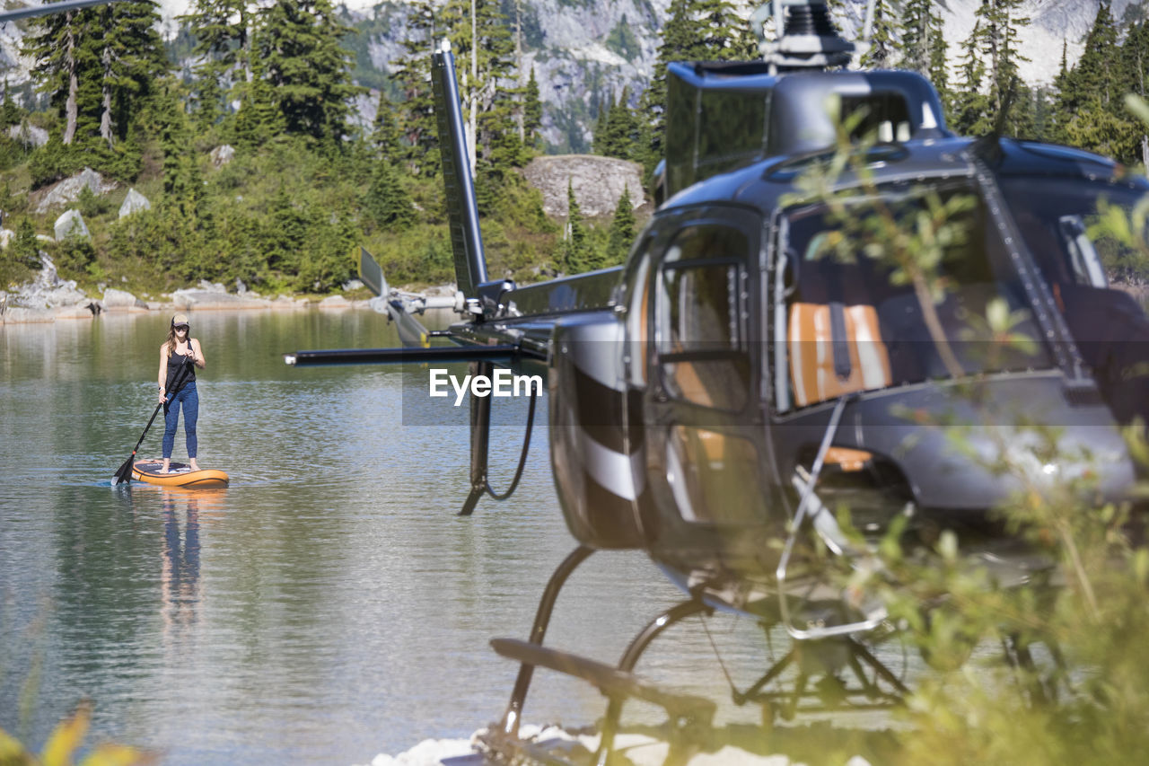 Woman paddle boards on remote lake accessed by helicopter.