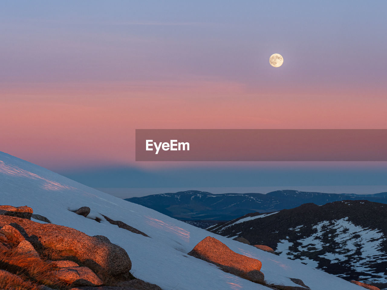 Cairngorms at sunset with colorful belt of venus and the rising moon in the sky during  winter