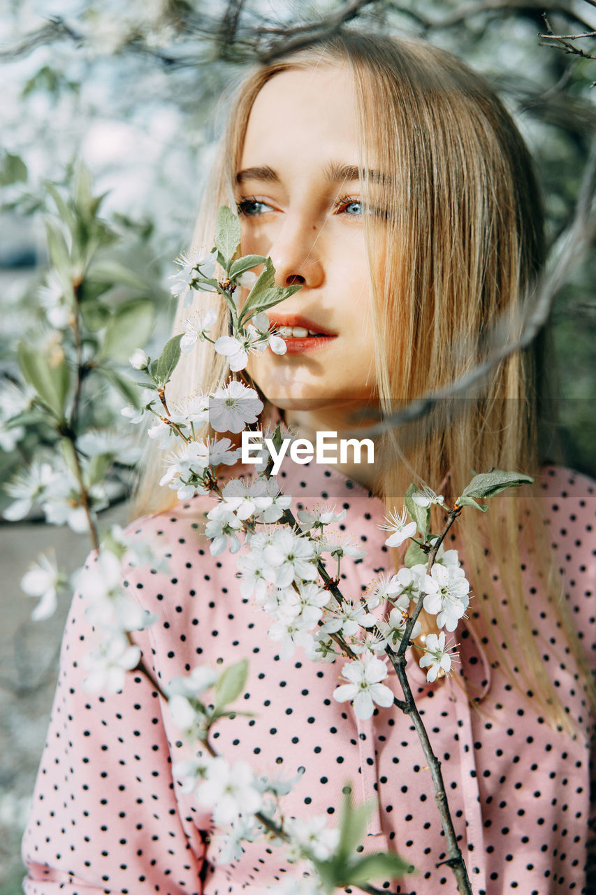 Portrait of young woman standing against plants