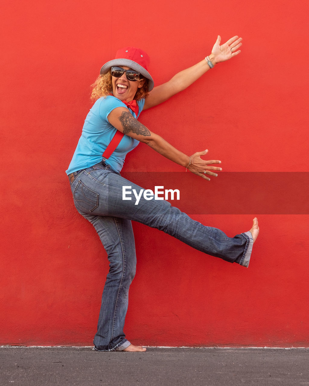 Full length portrait of mature woman dancing by red wall