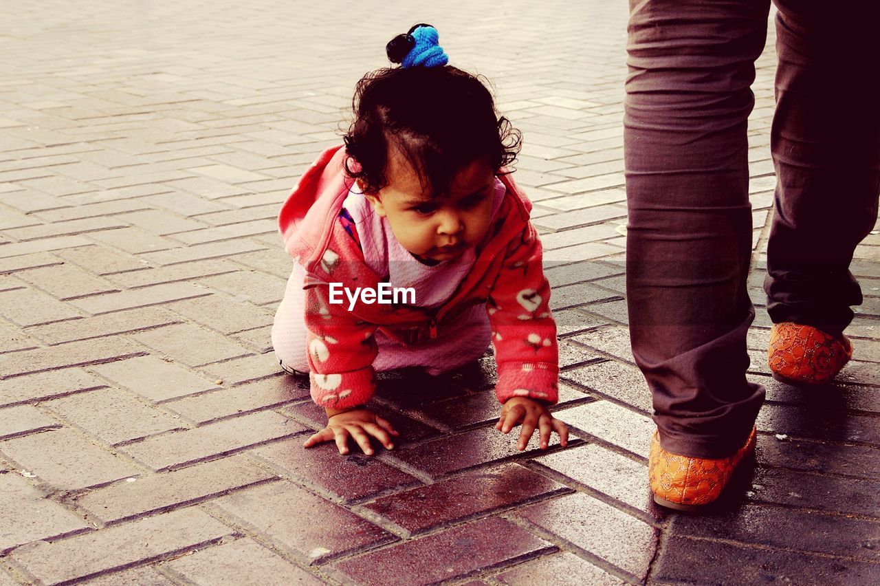 Cute baby girl crawling on footpath