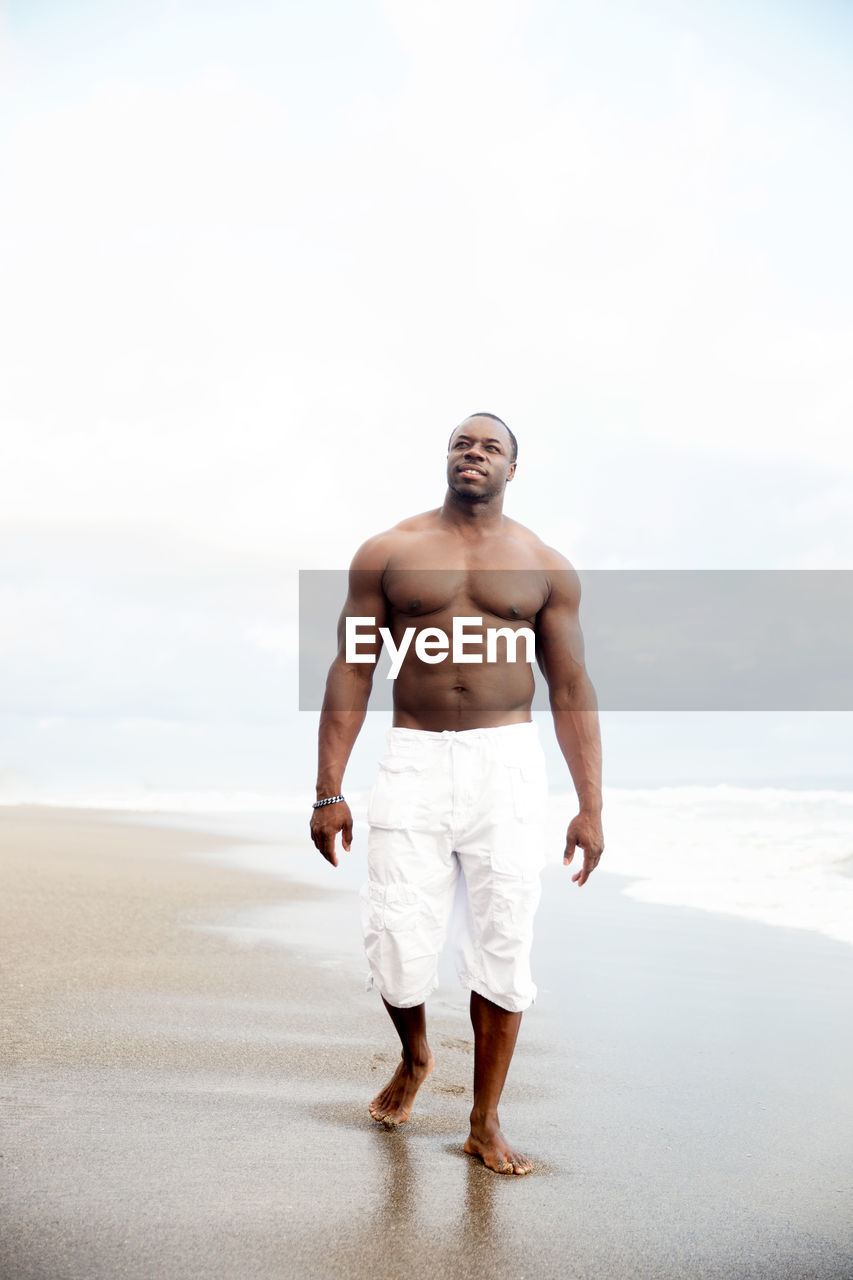 Handsome big body bilder black man walking by ocean side 