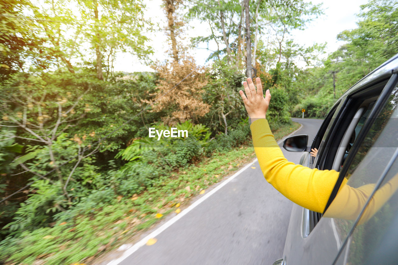 Cropped image of hand from car window on street