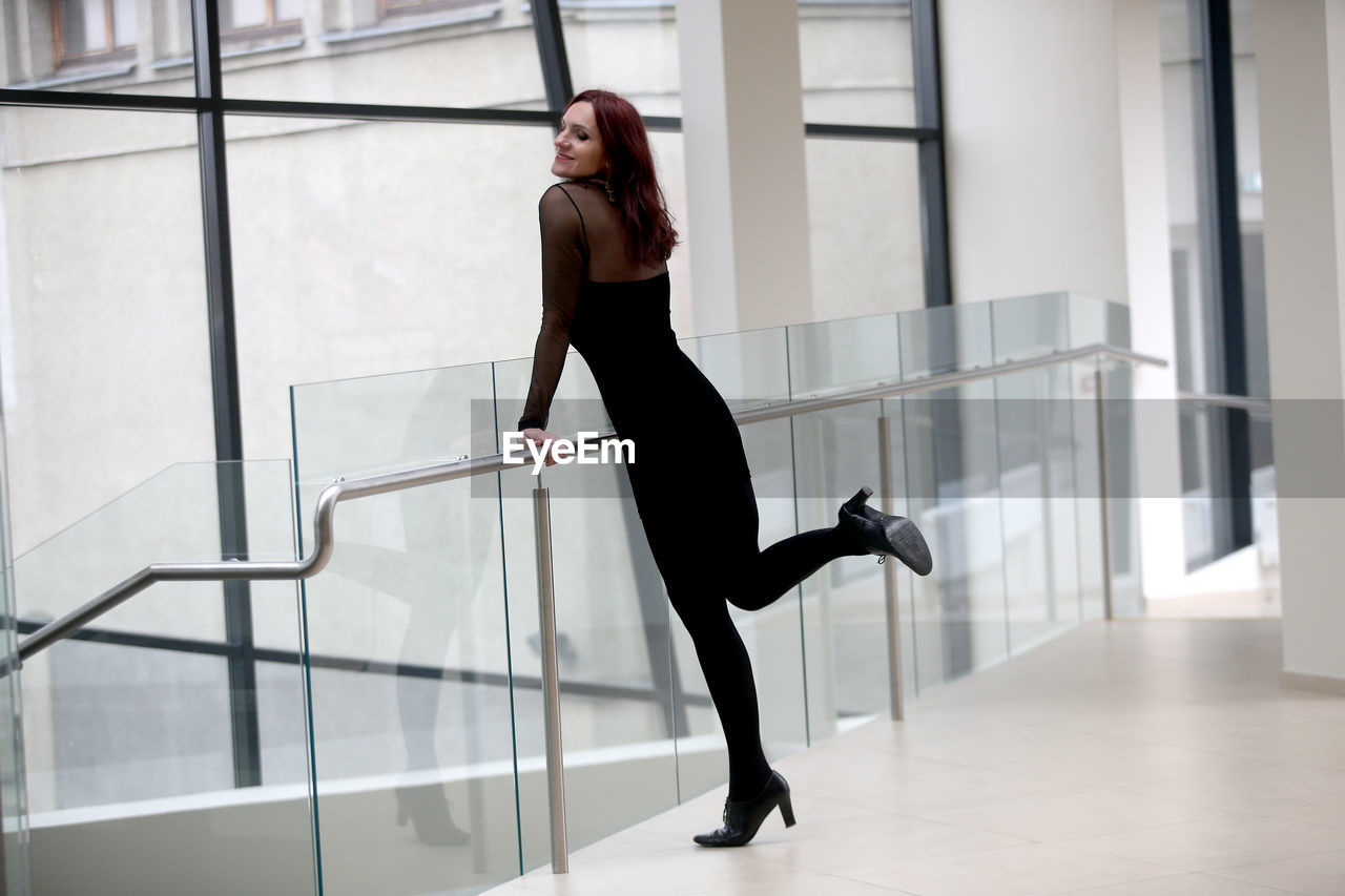 one person, adult, women, young adult, full length, indoors, architecture, lifestyles, business, side view, hairstyle, fashion, person, office, high heels, businesswoman, clothing, motion, long hair, black, corporate business, female, staircase, window, choreography, standing, elegance, dancing