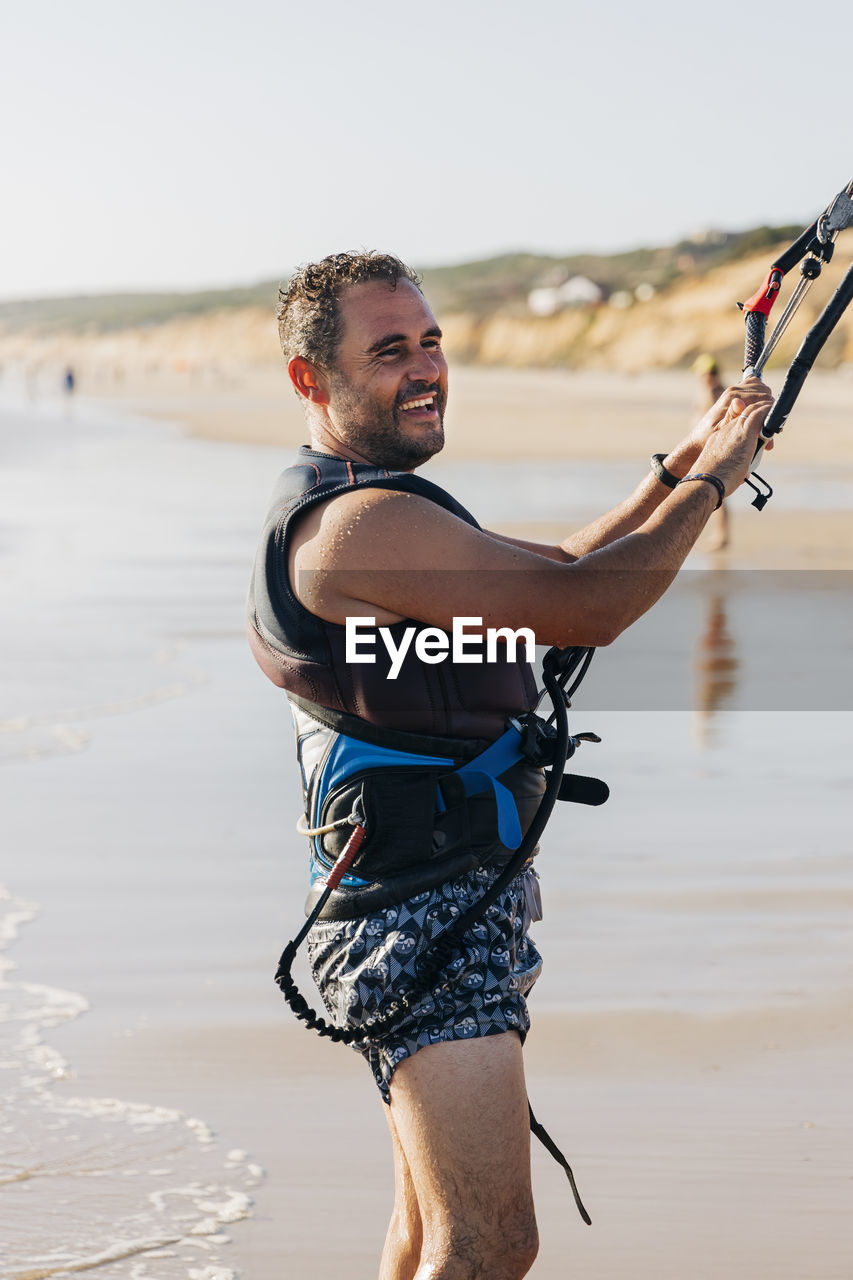 Man with kiteboarding equipment at beach during sunny day