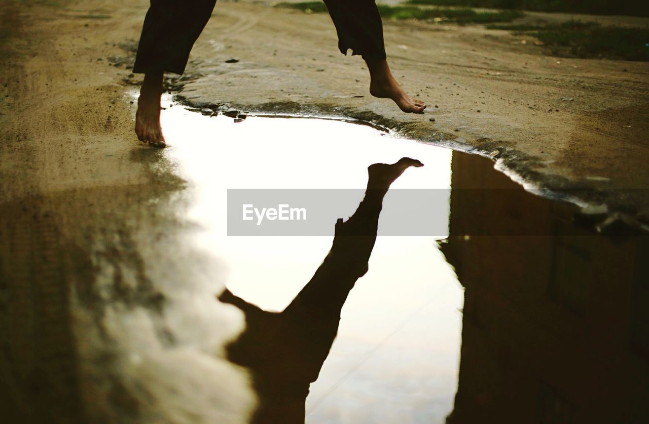 Low section of man jumping over puddle