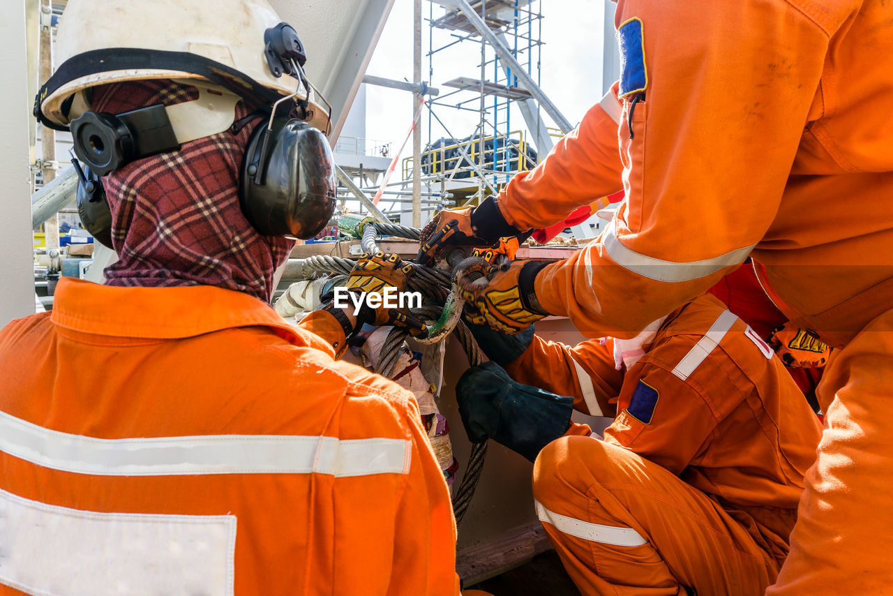 Construction workers preparing sling for heavy lifting of structure frame on a construction barge 