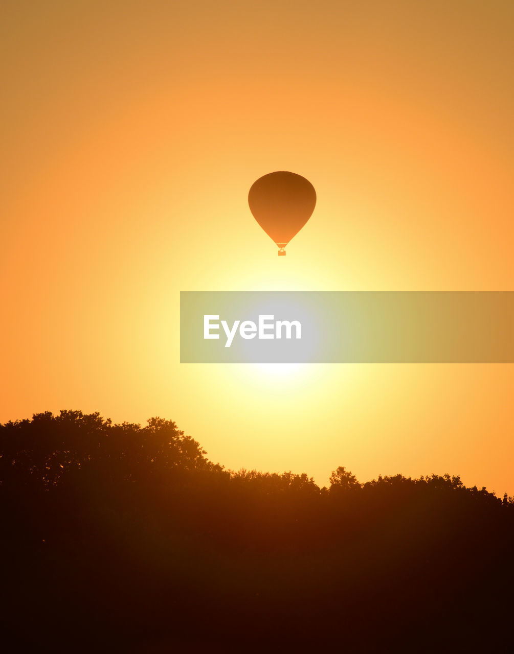 SILHOUETTE OF HOT AIR BALLOON AGAINST ORANGE SKY