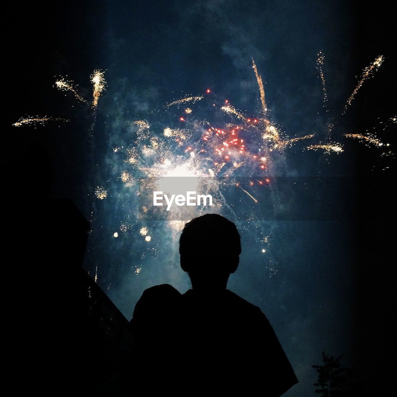 Low angle view of silhouette man against fireworks in night sky