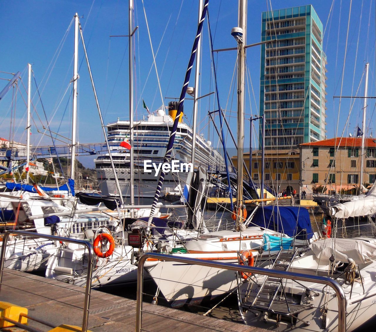 Sailboats moored at harbor against blue sky