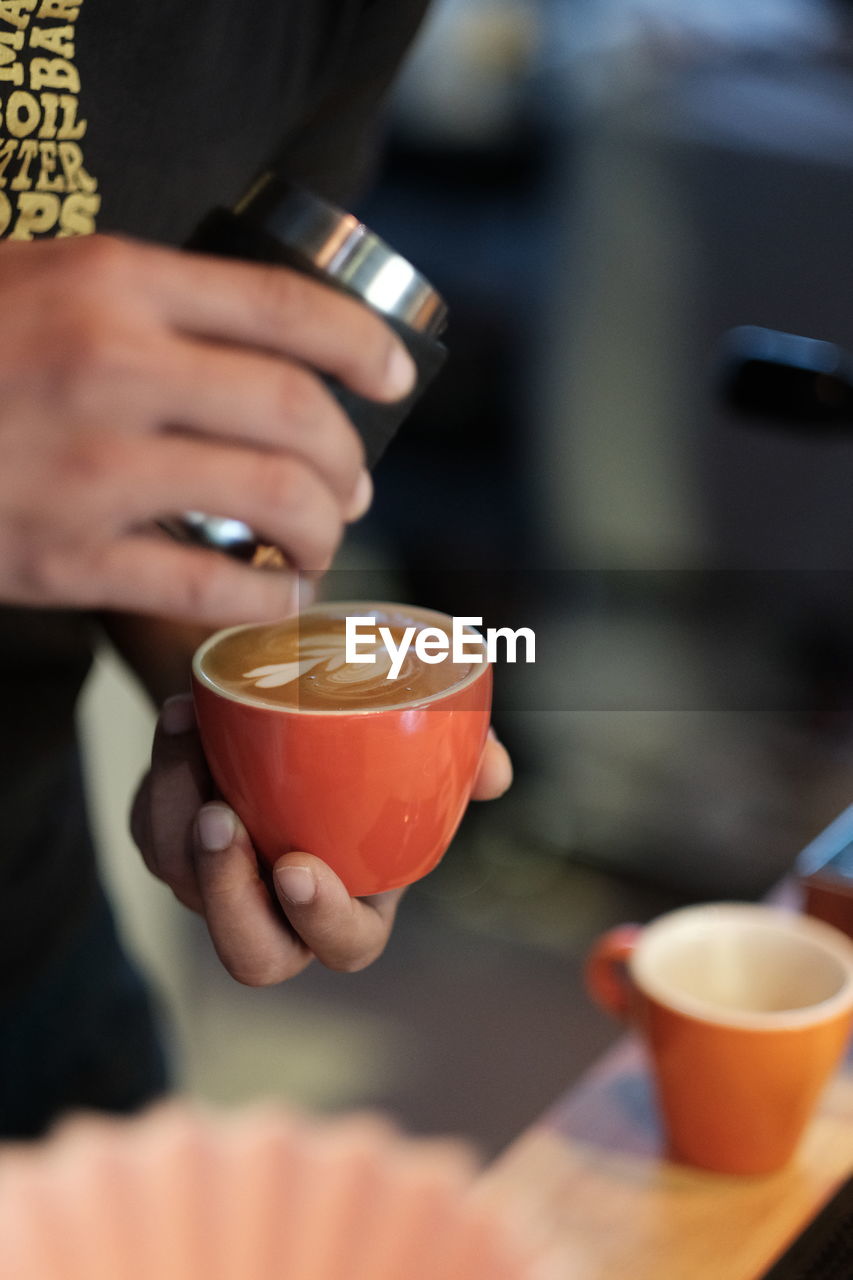 Cropped image of person pouring coffee in cup
