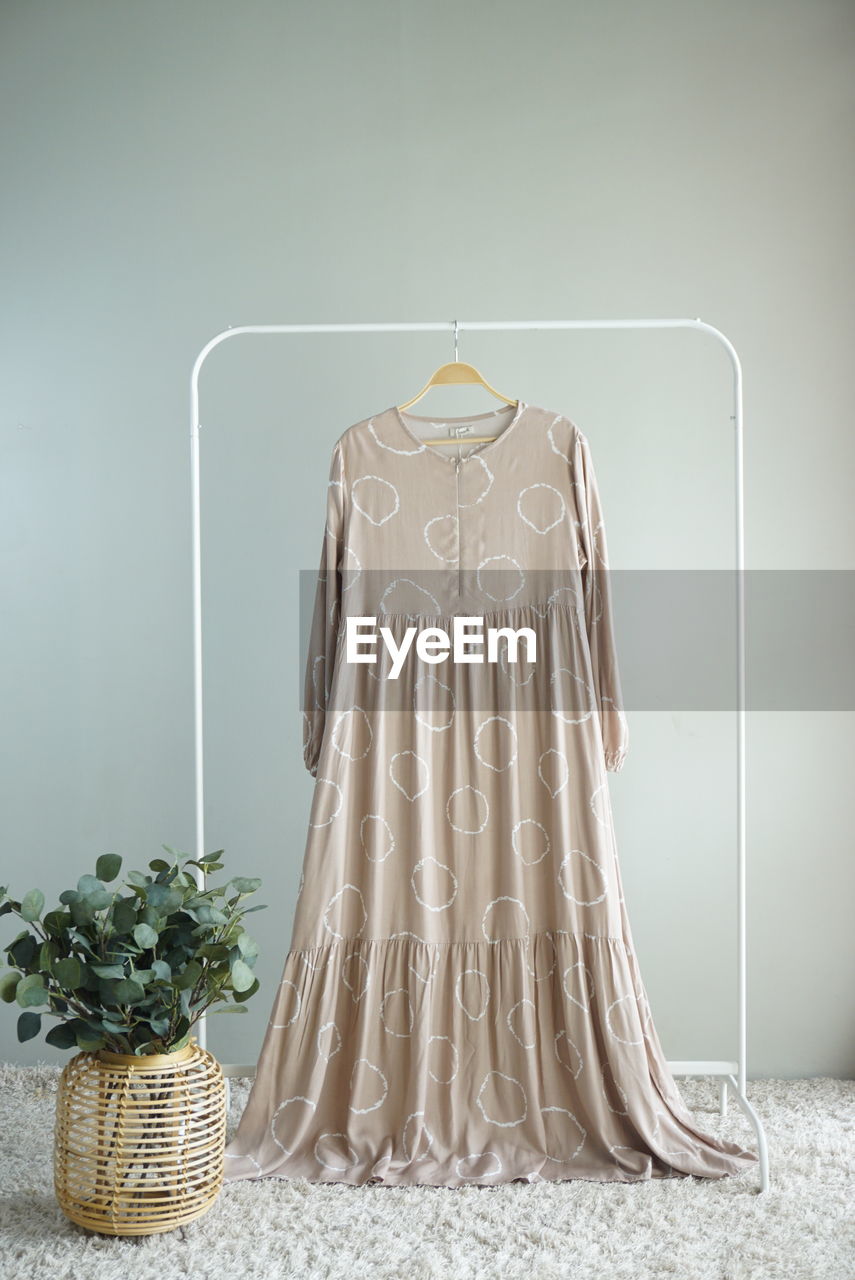 CLOTHES HANGING IN BASKET ON TABLE AGAINST WALL