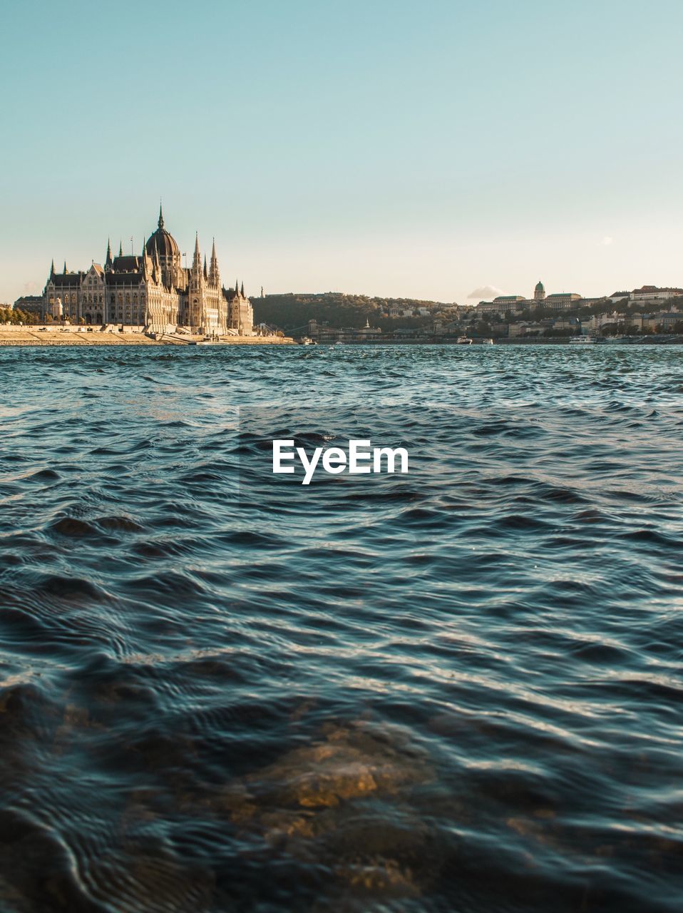 Hungarian parliament building by river against sky