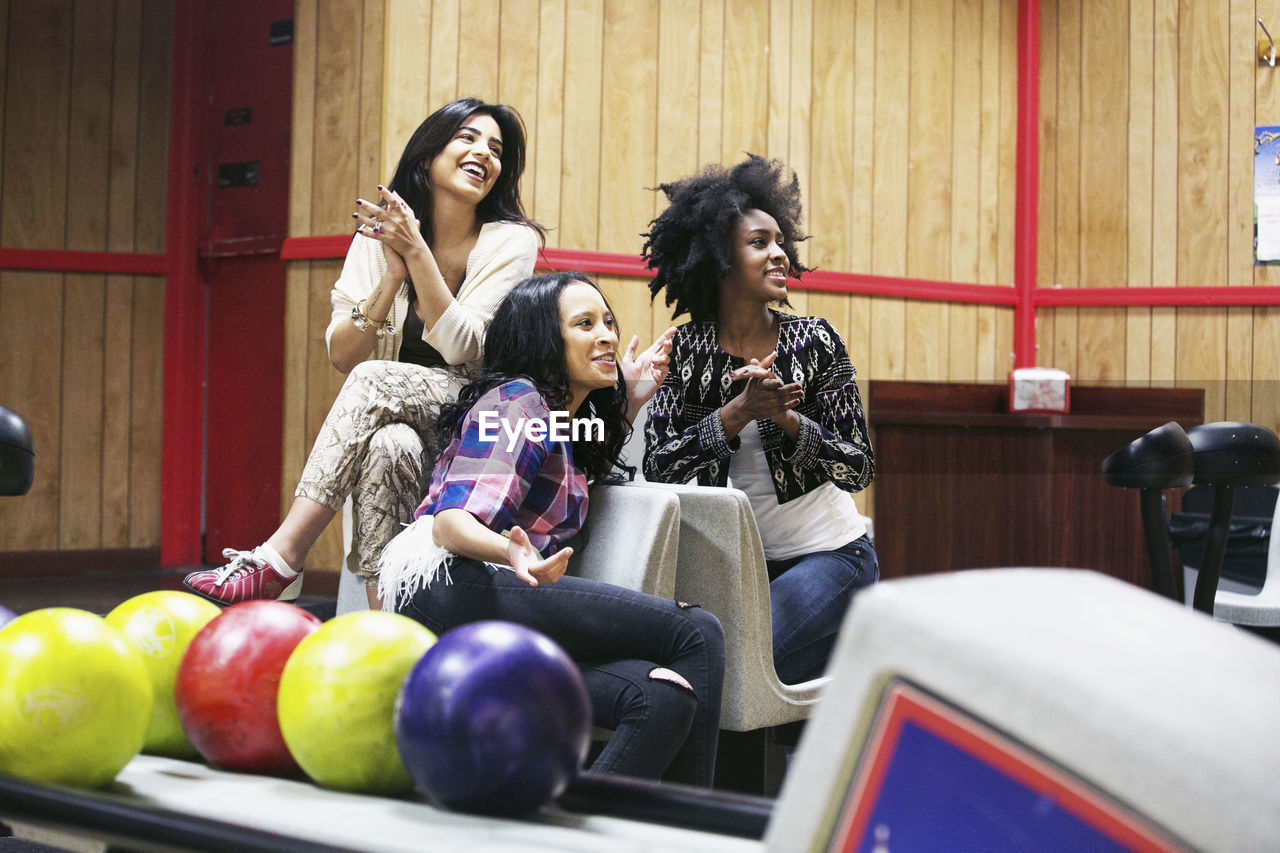 Three young women hanging out at a bowling alley