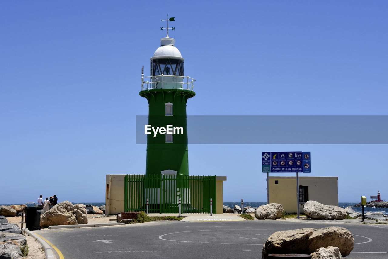 LIGHTHOUSE AMIDST BUILDINGS AGAINST CLEAR SKY