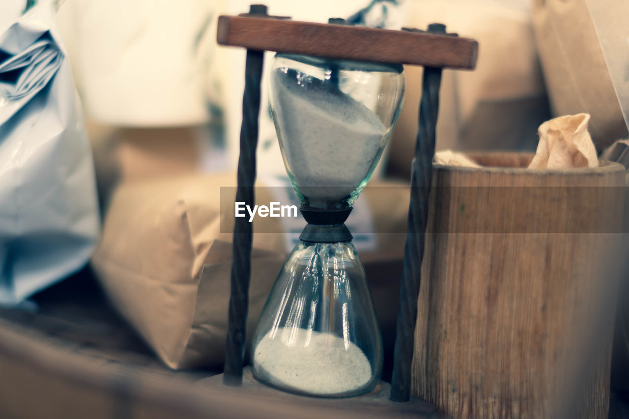 CLOSE-UP OF CLOCK IN GLASS ON TABLE