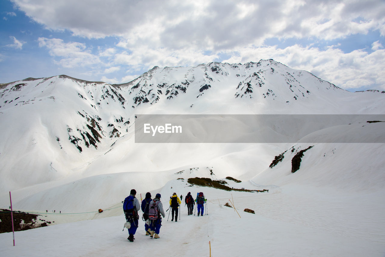 People walking on snowcapped mountain against sky