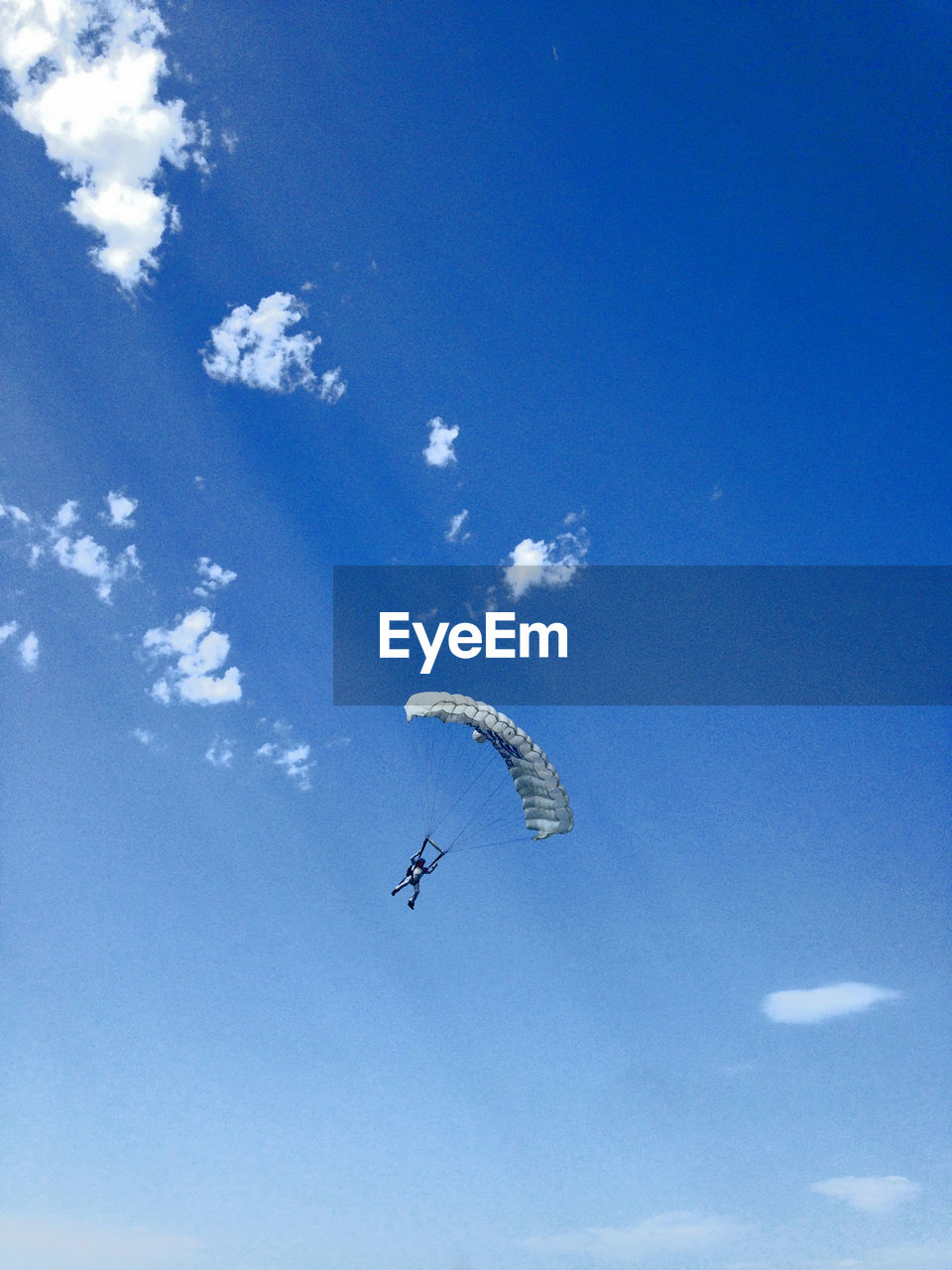 Low angle view of man paragliding against blue sky