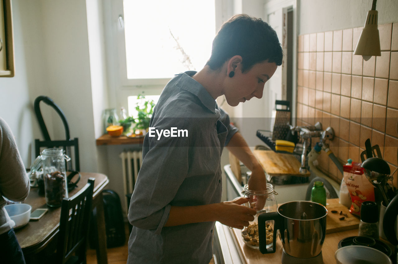 Side view of woman cooking in kitchen at home