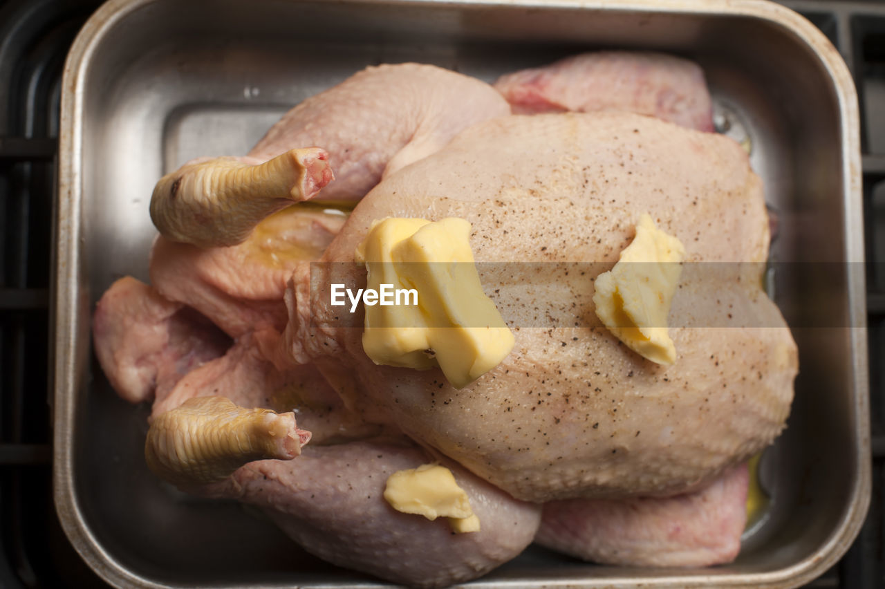 High angle view of raw chicken with butter on roasting pan
