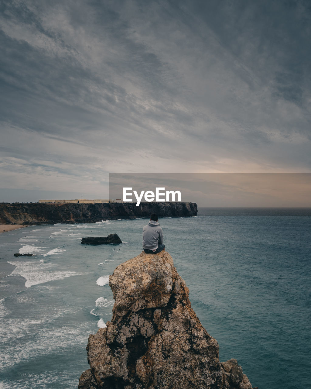 REAR VIEW OF PERSON LOOKING AT SEA AGAINST SKY