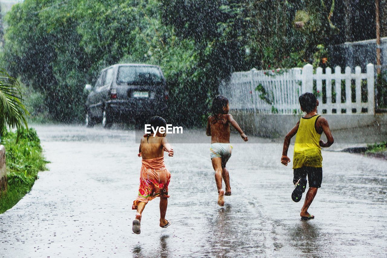 FULL LENGTH OF CHILDREN ON WET UMBRELLA