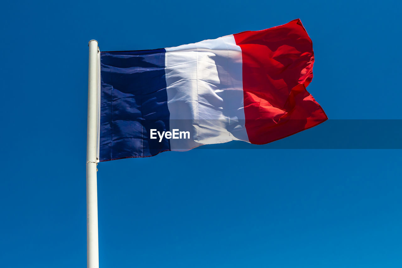 Low angle view of french flag waving against clear blue sky