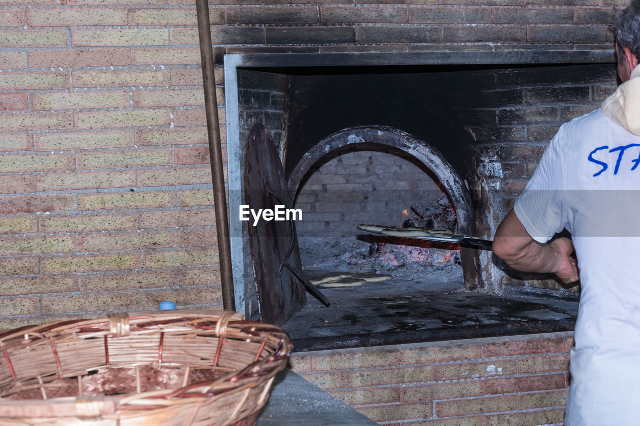 MIDSECTION OF MAN WORKING IN WICKER BASKET