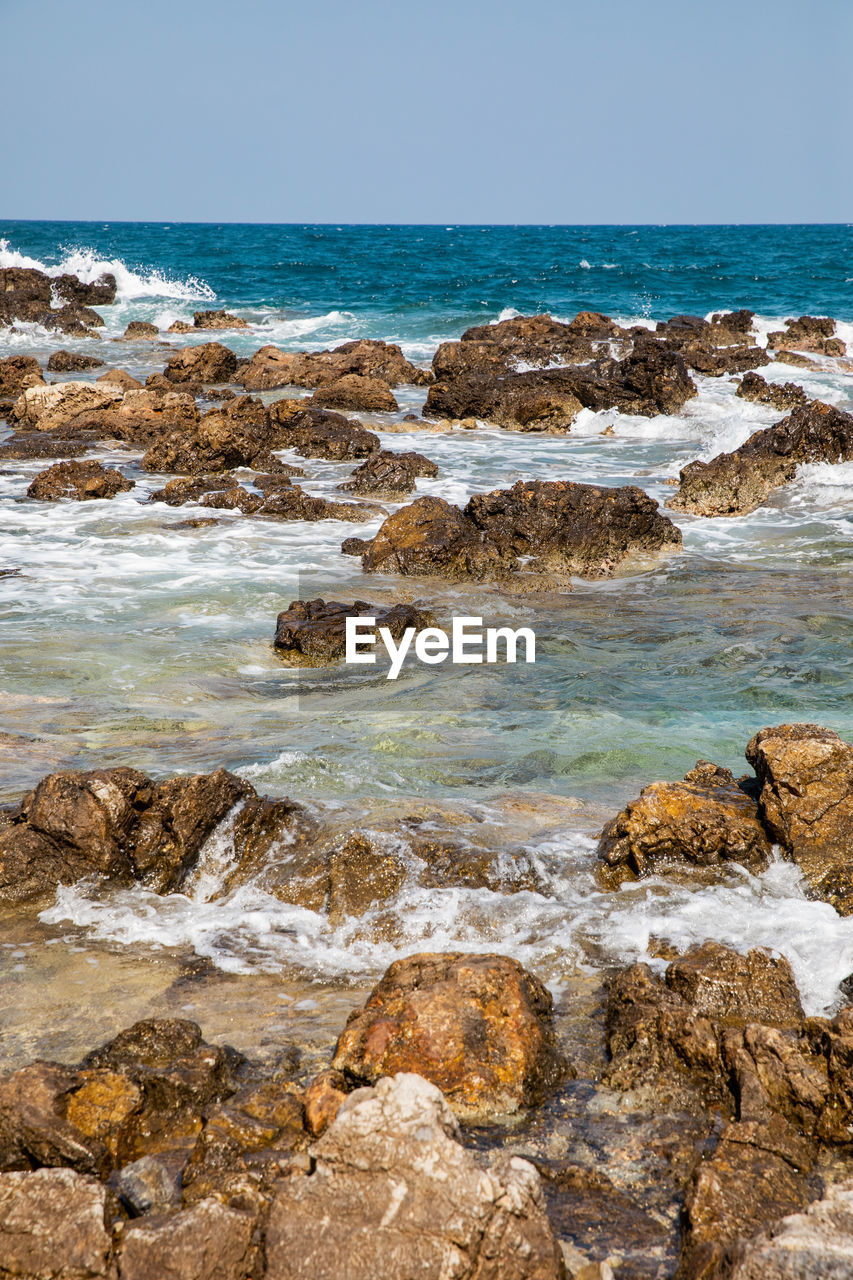 SCENIC VIEW OF ROCKY BEACH AGAINST SKY
