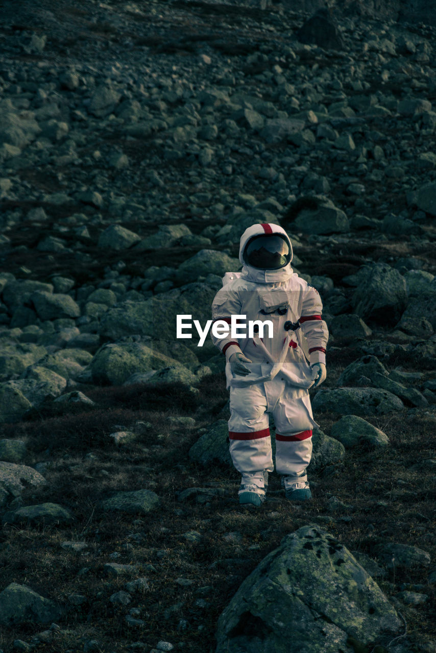 Astronaut standing on land against mountain