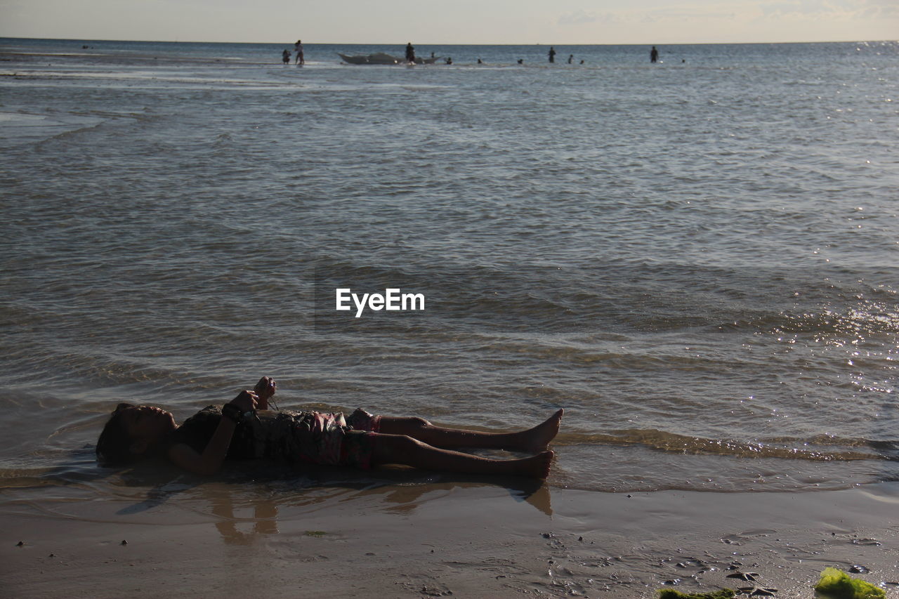 Young woman lying on shore at beach