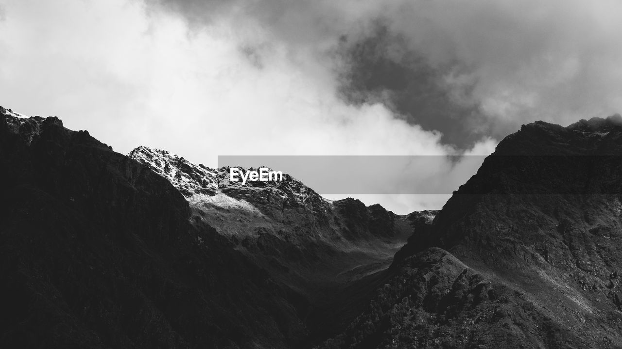 mountain, environment, cloud, landscape, sky, scenics - nature, nature, beauty in nature, black and white, mountain range, monochrome, land, monochrome photography, travel, no people, travel destinations, mountain peak, snow, outdoors, rock, non-urban scene, tourism, fog, activity, panoramic, geology, darkness, tranquility, extreme terrain, day