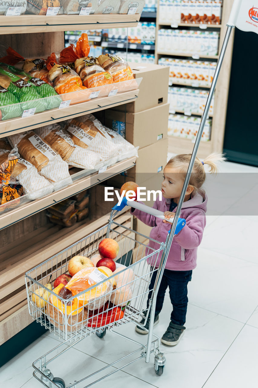 FULL LENGTH OF GIRL HAVING FOOD AT STORE