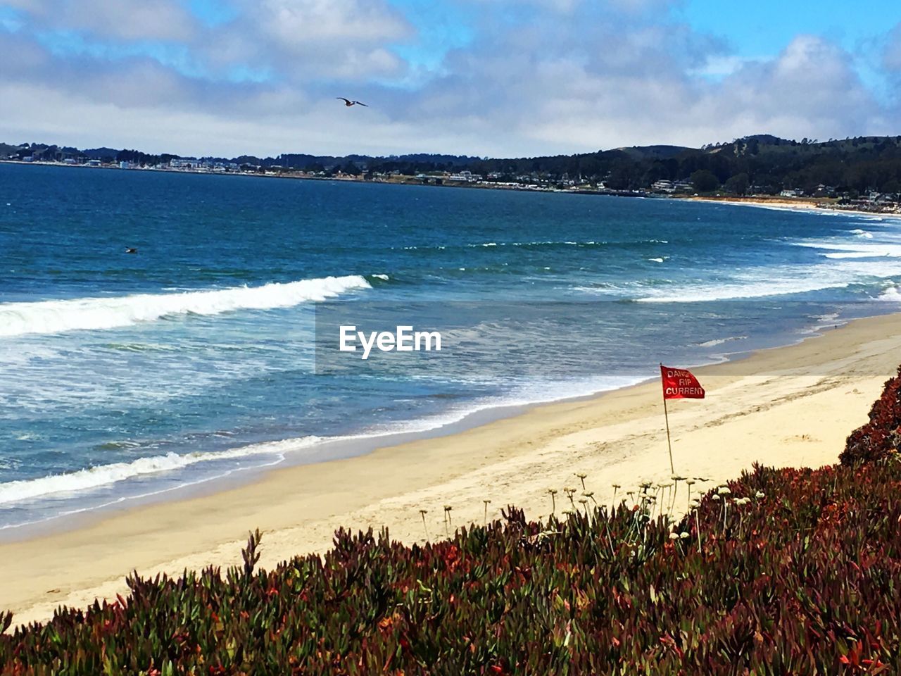 Scenic view of beach against cloudy sky