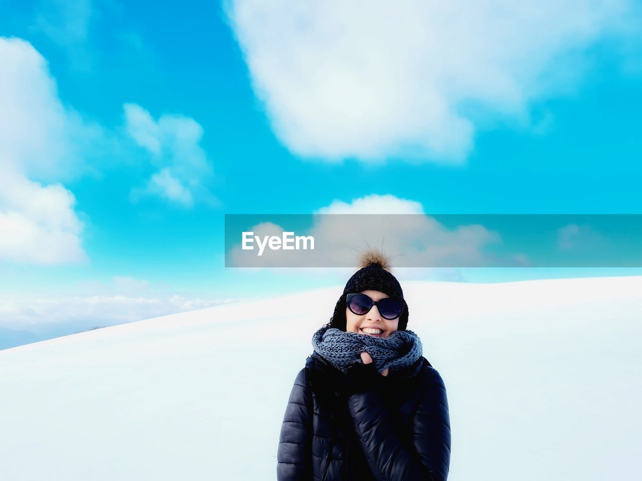 Smiling woman with winter clothes wrapped in white mountain landscape