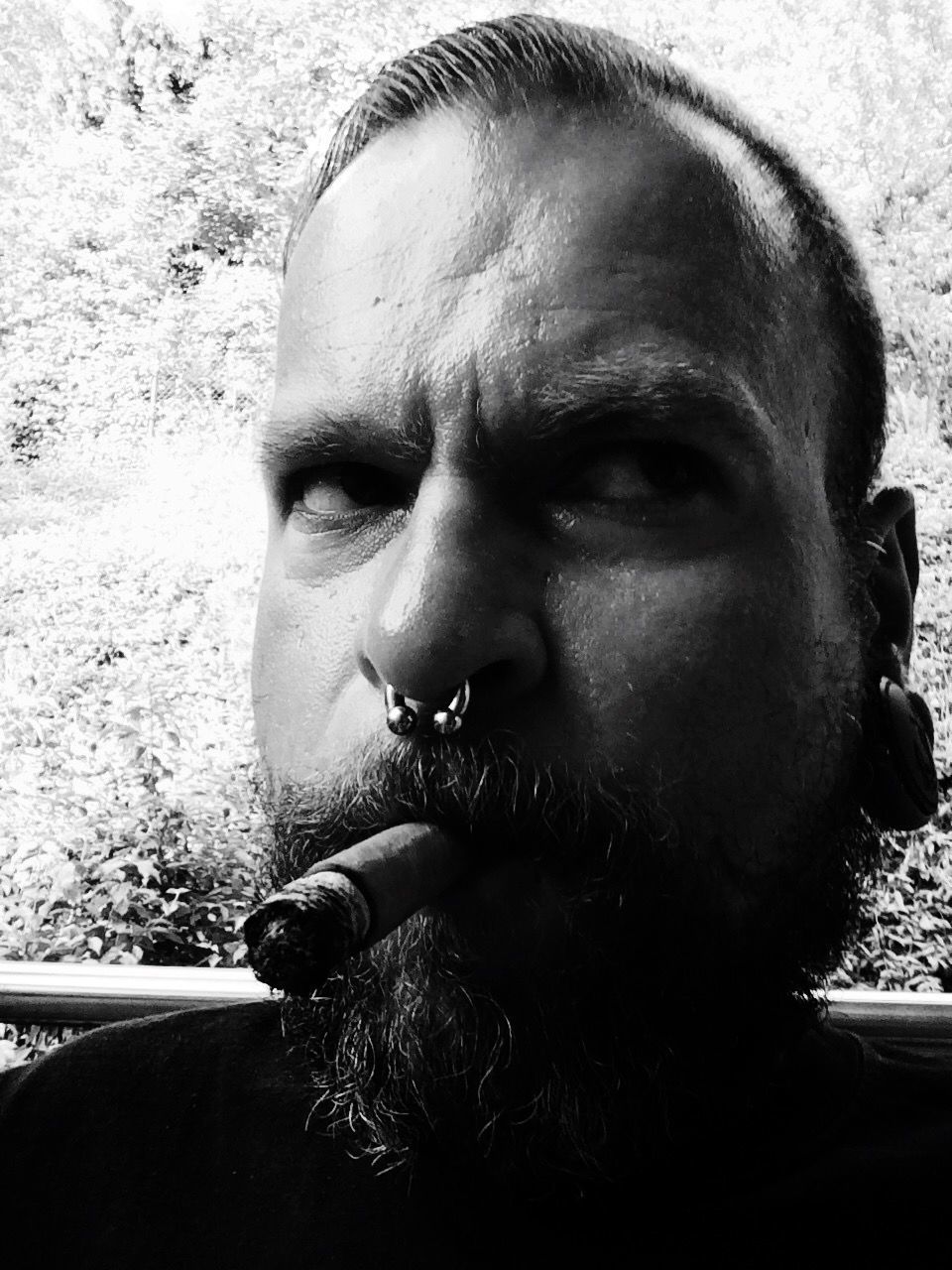 Close-up of mid adult man smoking cigar with pierced nose