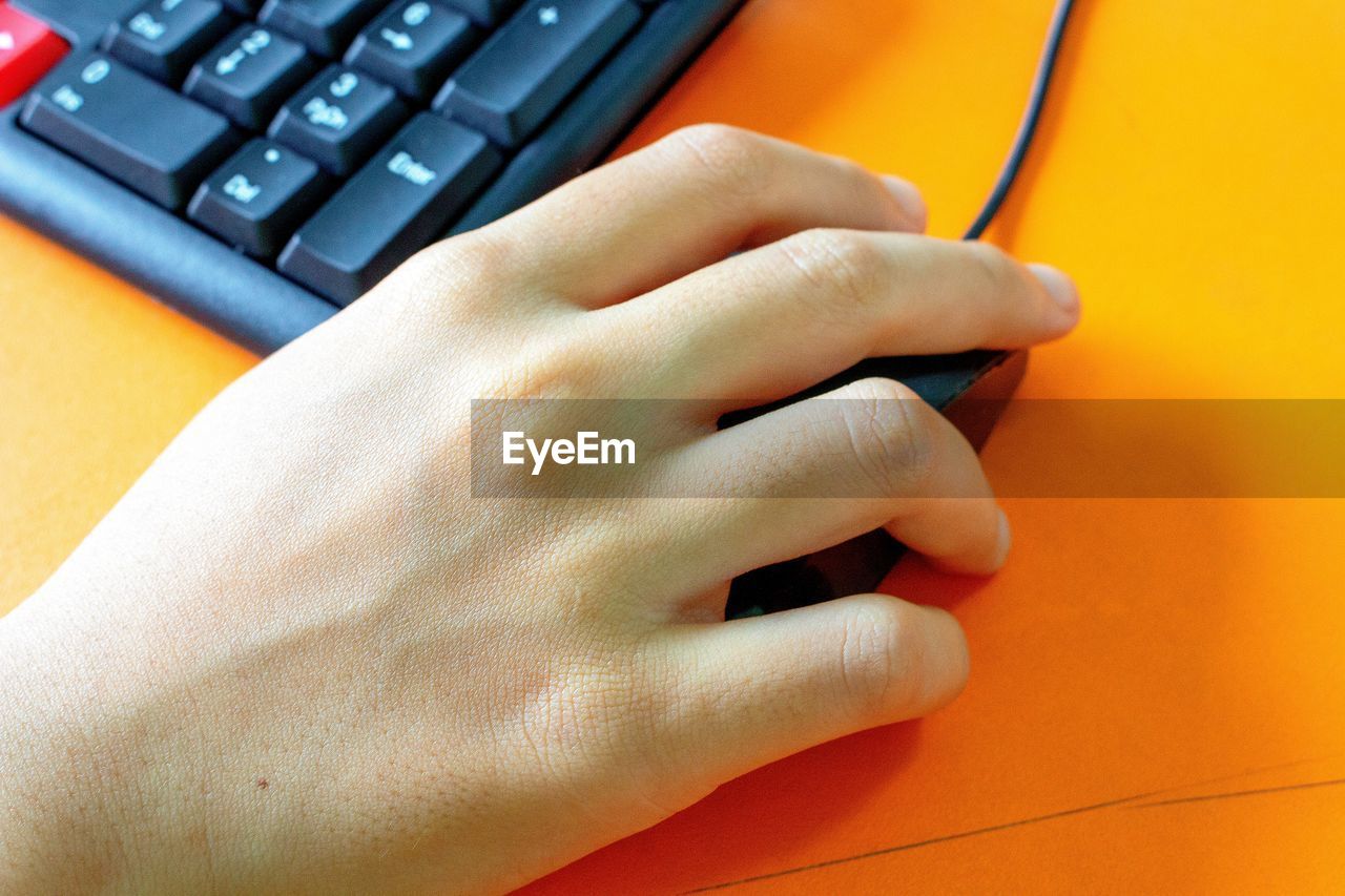 Cropped hand holding computer mouse on desk in office