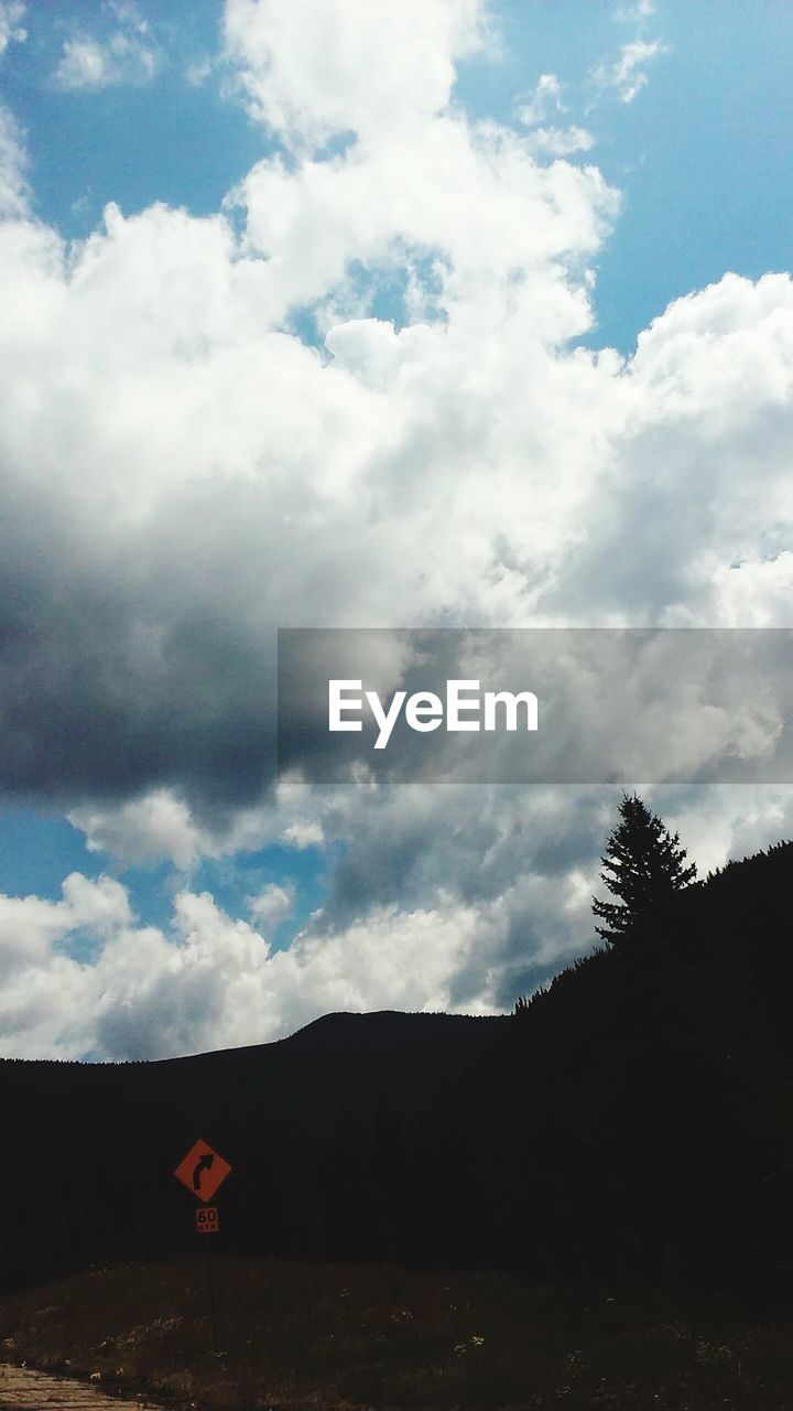 TREES ON LANDSCAPE AGAINST CLOUDY SKY