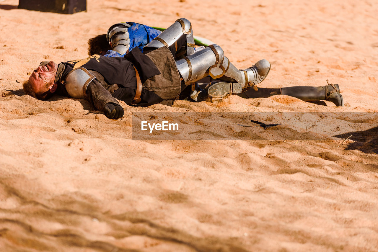 MIDSECTION OF MAN LYING ON SAND
