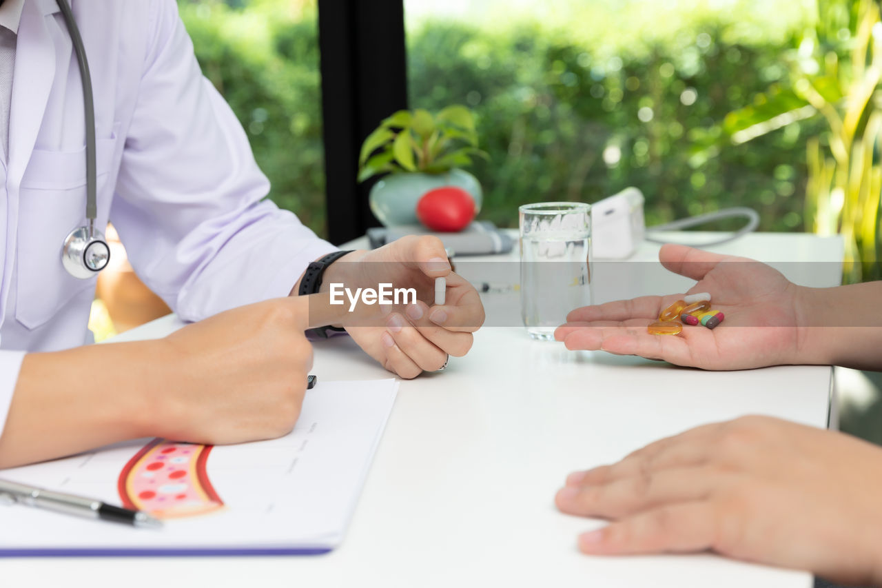 Midsection of doctor giving medicine to patient in medicine in clinic