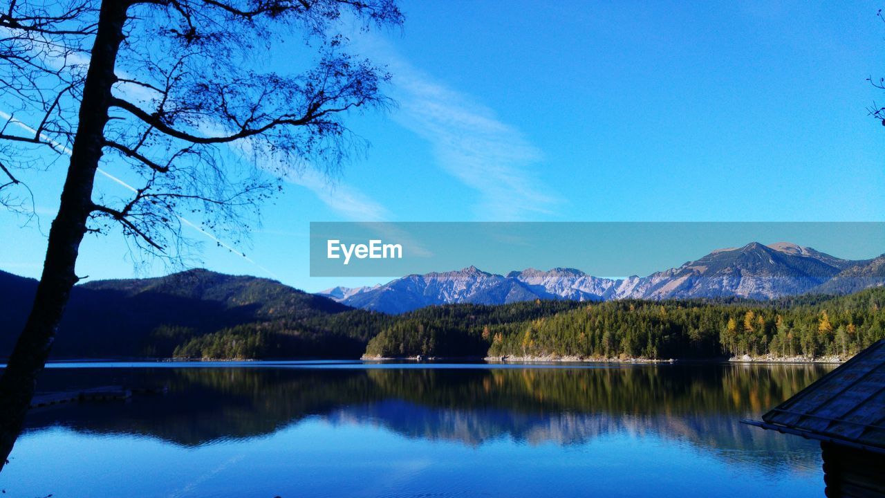 Mountains and trees reflecting in lake against sky