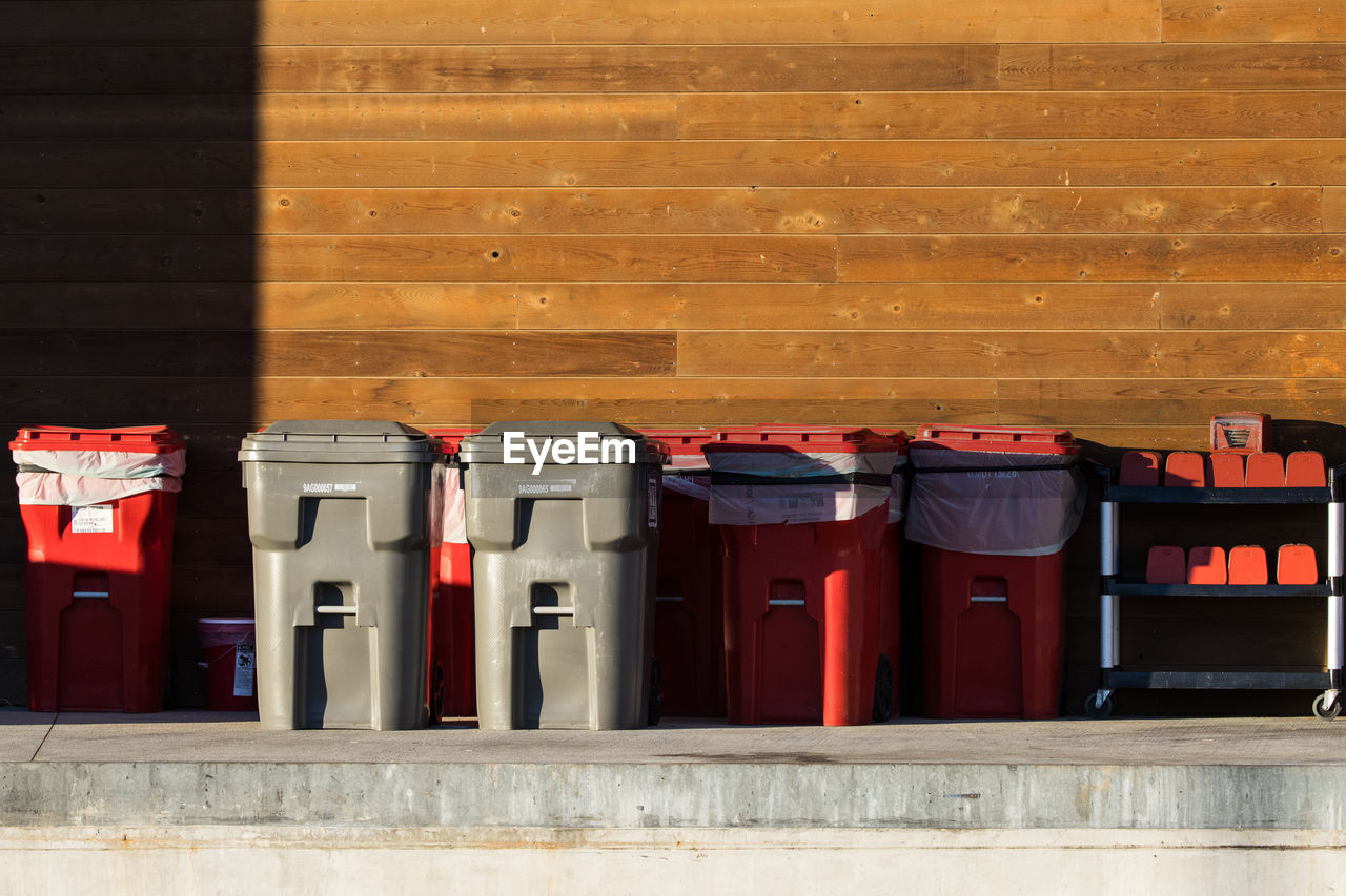 Garbage can by wooden wall outdoors