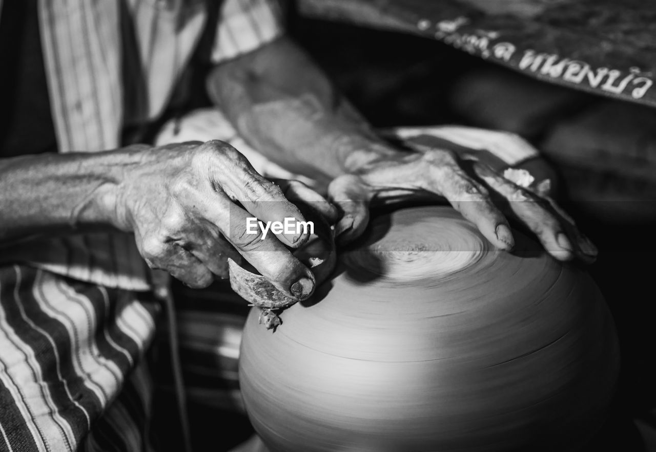 Midsection of man making pottery in workshop