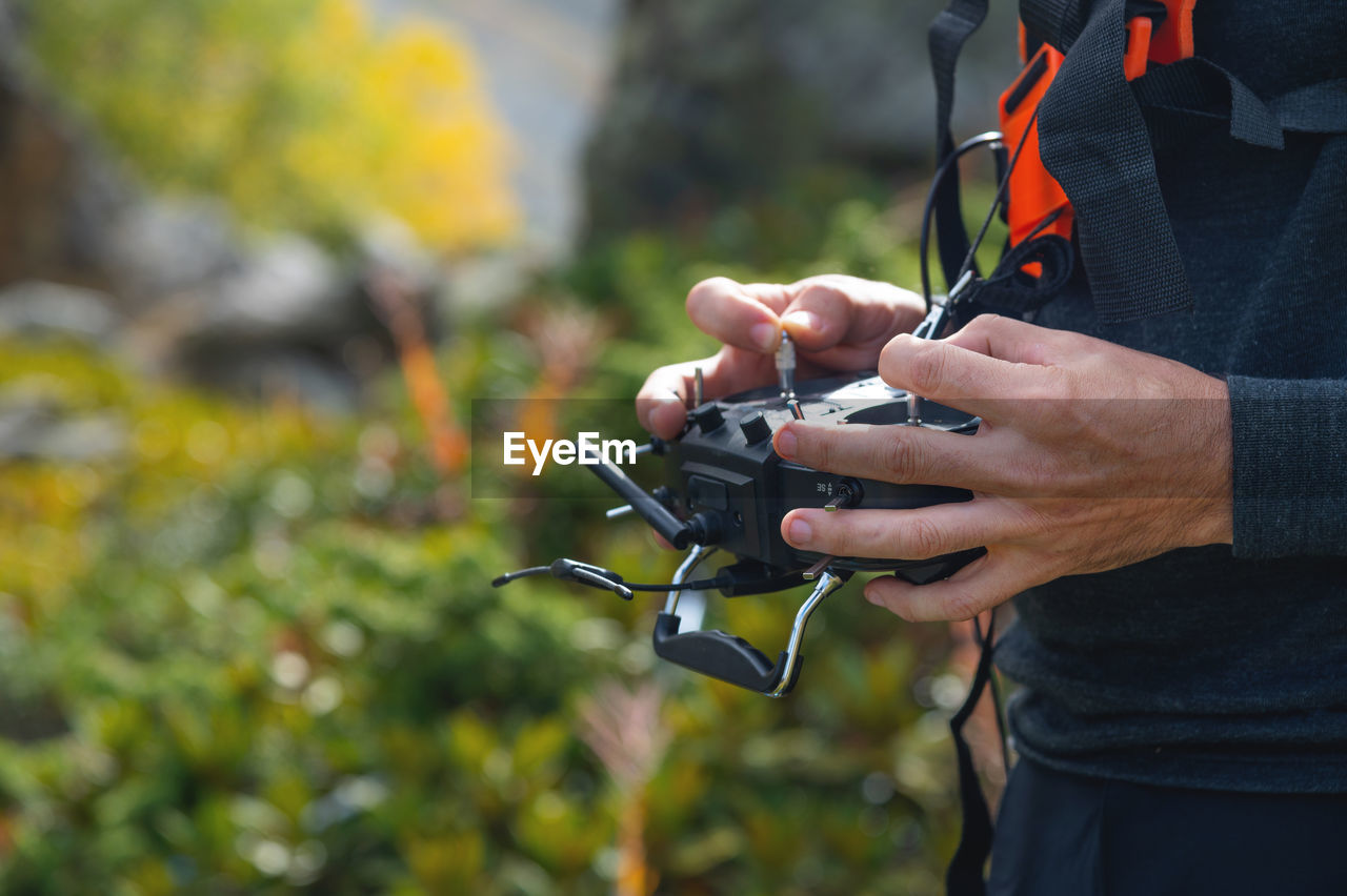 Close-up of a man's hands holding a remote control to control an fpv racing drone. flying an