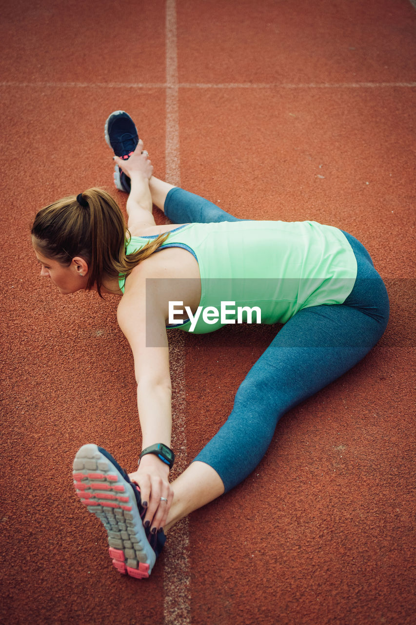 High angle view of young woman exercising on sports track