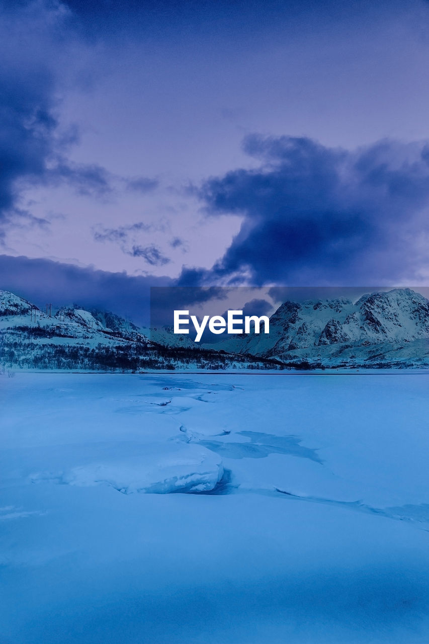 Scenic view of frozen lake and snowcapped mountains against sky