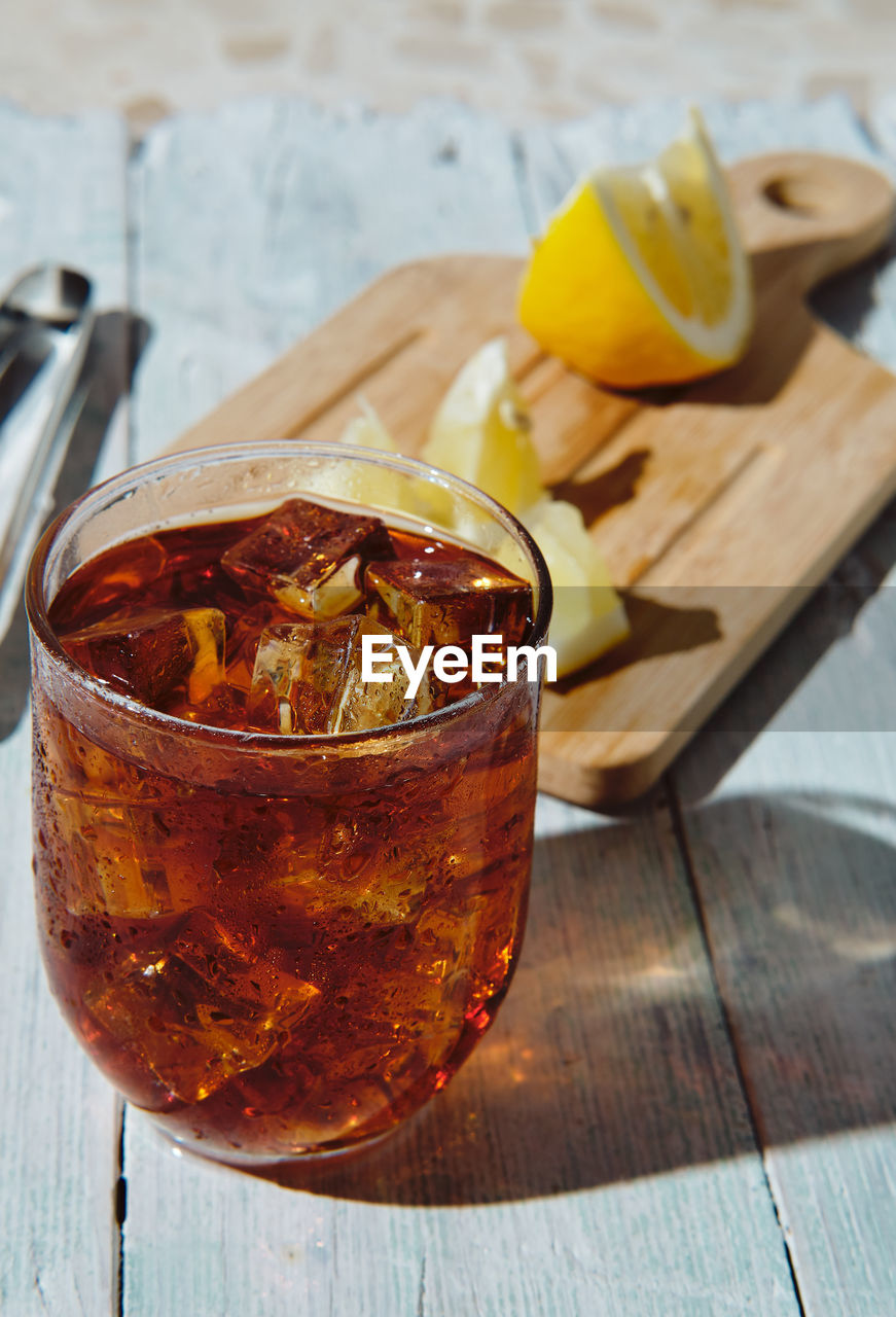 Very cold cola on a white background with ice and lemon