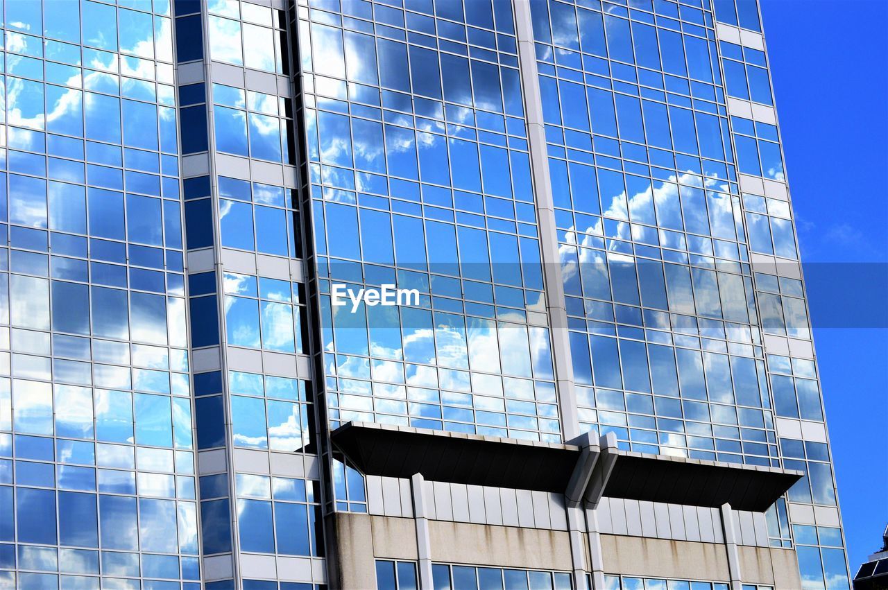 Low angle view of glass building with sky reflection